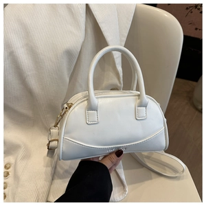 Detail of white moon-shaped mini bag with FASHION lettering and golden metal buckles