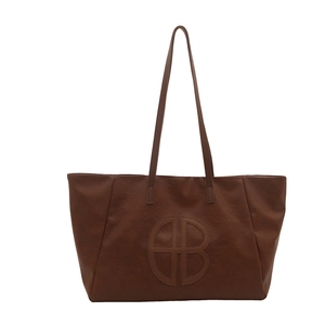 Large dark brown leather tote bag with circular cutout logo and slim shoulder straps