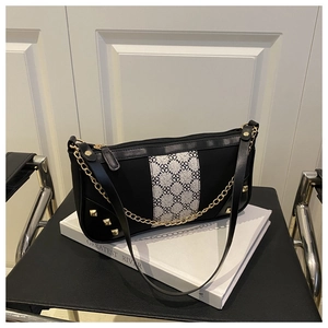 Detail of black shoulder bag with clover pattern, gold studs and dual metallic chain strap