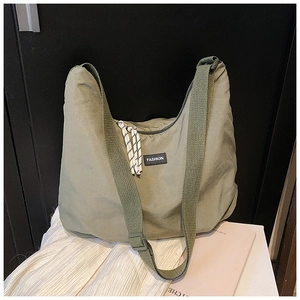 Dettaglio della borsa tote in tela verde oliva con ampia tracolla e patch logo fashion