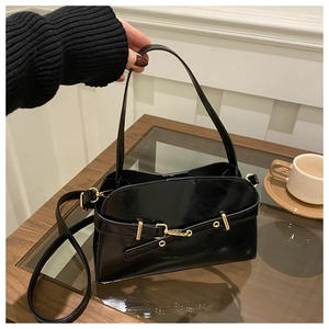 Detail einer schwarzen glänzenden Ledertasche mit Trageriemen und Metallschmuck-Schnalle