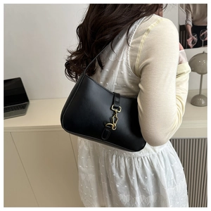 Détail d'un sac sous le bras en cuir noir vintage avec une boucle métallique dorée chic