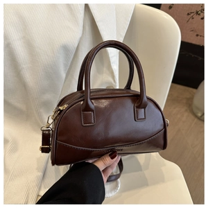 Detail of dark brown Boston bag with embossed logo and glossy faux leather texture