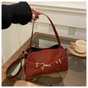 Detail der dunkelroten Muscheltasche mit glänzendem Lederfinish und goldenen Metallschnallen
