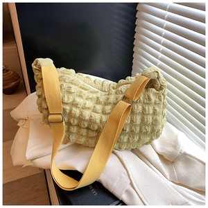 Detail of light green bubble textured crossbody bag with adjustable yellow canvas strap