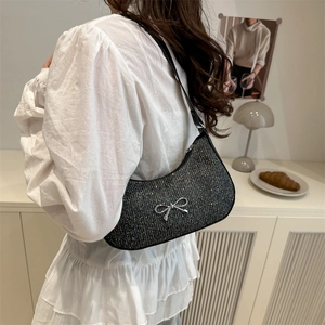 Sparkly black glitter shoulder bag with silver bow accent on model in cozy interior