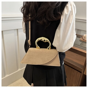 Detail of light camel suede leather bag featuring a unique gold metal handle and strap