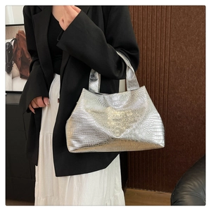 Detailed view of silver crocodile embossed shoulder bag on model in stylish black outfit
