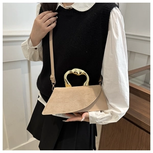Detail of beige irregular crossbody bag featuring a unique gold flowing metal handle