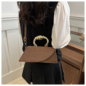 Brown dual-texture handbag with curved gold handle and crossbody strap on a model