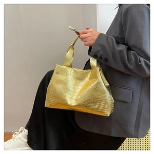 Detail of golden crocodile pattern shoulder bag with glossy finish and dual handles