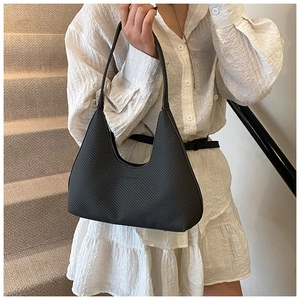 Chic black woven hobo bag with half-moon shape worn by model in casual minimalist setting