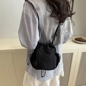 Sac seau minimaliste en nylon noir avec cordon de serrage, poches filet et bandoulière