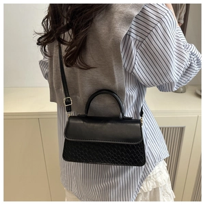 Close-up of black crossbody bag with mixed textures and elegant pale gold hardware