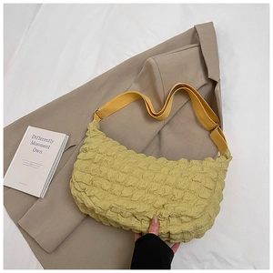 Detail of soft pleated fabric texture and canvas strap on a light yellow cloud tote bag