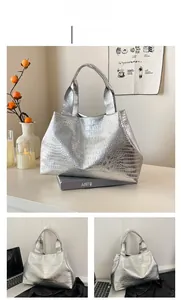 Detail showing crocodile texture on a silver tote bag with double handles in a lifestyle setting