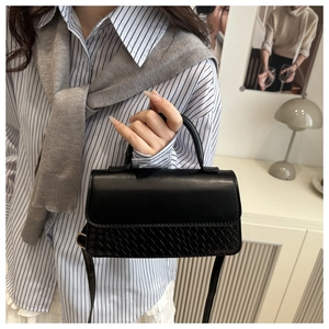 Detail showing vintage black crossbody bag with premium woven texture and smooth leather