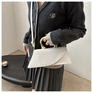 Detailed shot of white geometric handbag with gold metal handle and slim shoulder strap