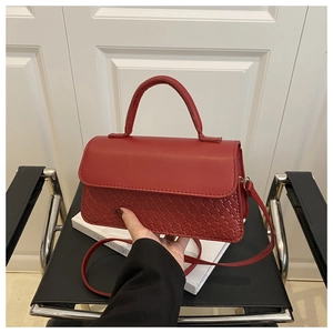 Close-up of red PU leather crossbody bag featuring woven texture and gold hardware