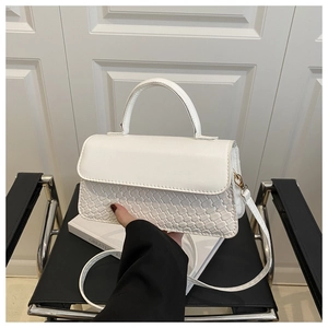 Detailed shot of white crossbody bag with woven texture, metal hardware and top handle