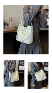 Detailed embroidery of bamboo leaves and pearl tassel on a beige canvas tote bag