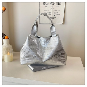 Chic silver faux crocodile tote bag displayed on an artistic book in a modern room
