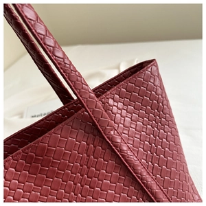 Close-up of deep red woven leather tote bag showing intricate grid texture and stitching
