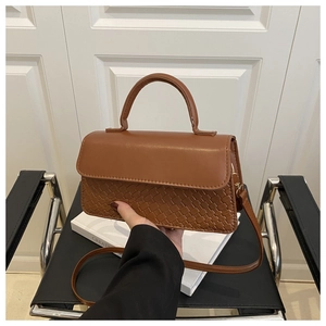 Close-up of caramel brown woven crossbody bag with matte finish and top handle