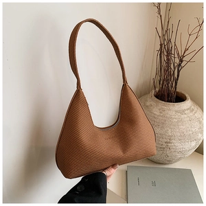 Close-up of brown woven texture and curved minimalist silhouette on a leather Hobo bag