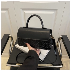 Detail of black woven texture and smooth leather patchwork on women crossbody bag