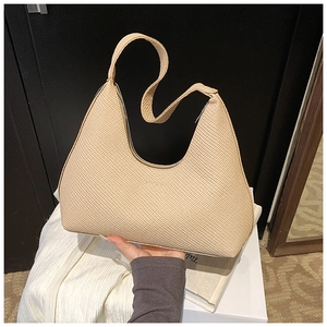 Detailed texture of beige woven hobo bag showing minimalist crescent shape and handle