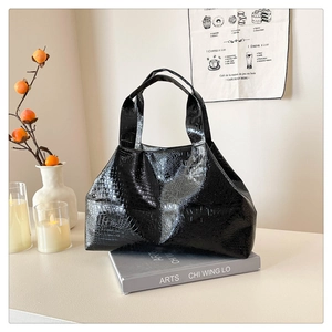 Detail of glossy black crocodile pattern shoulder bag on a minimalist art book