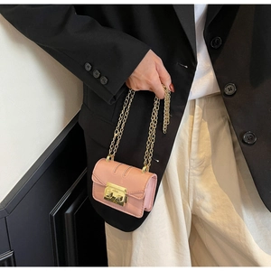 Détail d'un mini sac rose bandoulière avec fermoir doré sur une surface en cuir fin