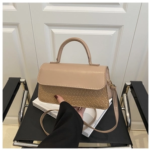 Detail of khaki leather handbag with woven texture and gold hardware on vintage chair