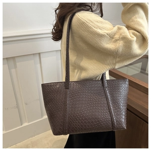 Detail of a deep brown woven leather tote bag featuring classic intrecciato texture pattern