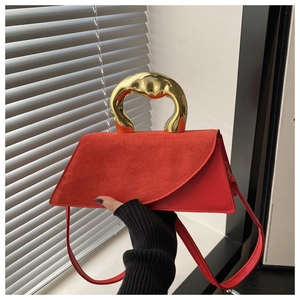 Detail of red leather tote bag showing unique golden metallic handle and suede texture