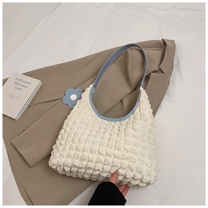 Detail of white bubble texture tote bag with light blue strap and flower charm