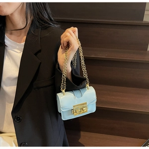 Gros plan d'un mini sac à chaîne bleu clair avec fermoir doré porté par un mannequin