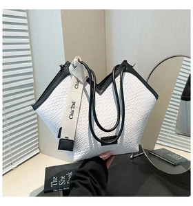 Detail of black and white embossed tote bag with a branded wide fabric shoulder strap