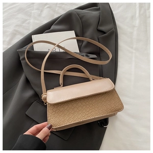 Detail of beige faux leather handbag featuring crocodile pattern and top handle design