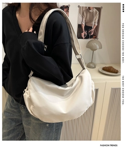Détail du sac à bandoulière blanc en forme de croissant porté par un mannequin