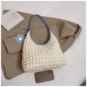 Detail of white popcorn textured shoulder bag with blue strap and floral charm accessory