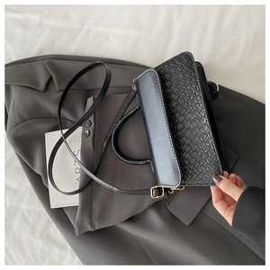 Side view of black crossbody bag featuring woven texture and adjustable shoulder strap