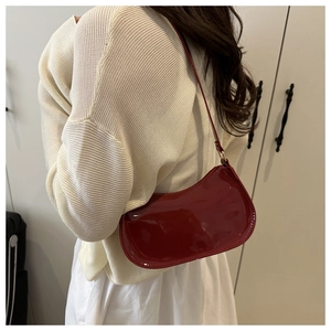 Detail of dark red patent leather hobo shoulder bag with glossy finish and sleek strap