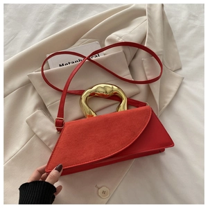 Detail of red leather crossbody bag featuring a unique organic-shaped golden metal handle