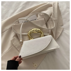 Detail of white geometric handbag with unique golden liquid metal handle and smooth leather