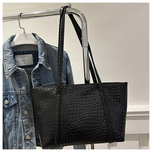 Detailed view of the black leather woven texture and straps on this large tote bag