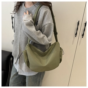 Vue détaillée d'un sac bandoulière demi-lune vert olive porté sur un sweat gris