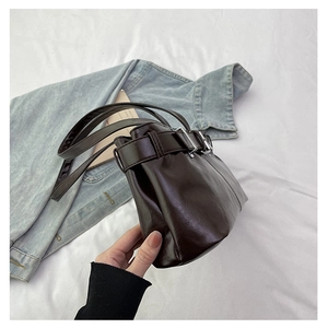 Dettaglio borsa a spalla in pelle marrone scuro con fibbia argento e sfondo denim