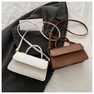 Detail of white and brown crossbody bags with faux crocodile texture on office blazer